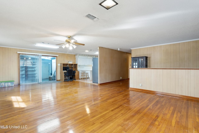 14071 Duckworth Rd, Gulfport, MS 39503 - unfurnished living room featuring light wood-style flooring, wooden walls, ceiling fan, crown molding, and baseboards