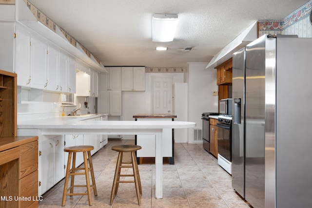 14071 Duckworth Rd, Gulfport, MS 39503 - kitchen featuring stainless steel refrigerator with ice dispenser, a peninsula, a breakfast bar area, light countertops, and gas range oven