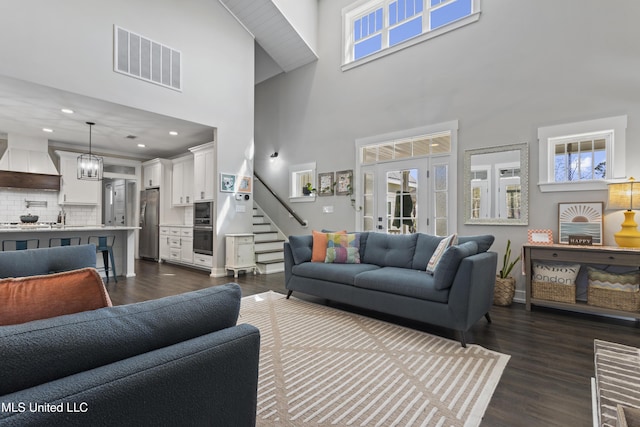 living room featuring stairway, dark wood-type flooring, visible vents, a towering ceiling, and recessed lighting
