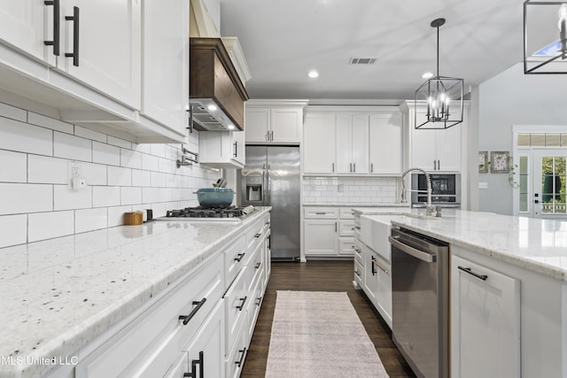 kitchen featuring visible vents, stainless steel appliances, white cabinetry, a sink, and light stone counters