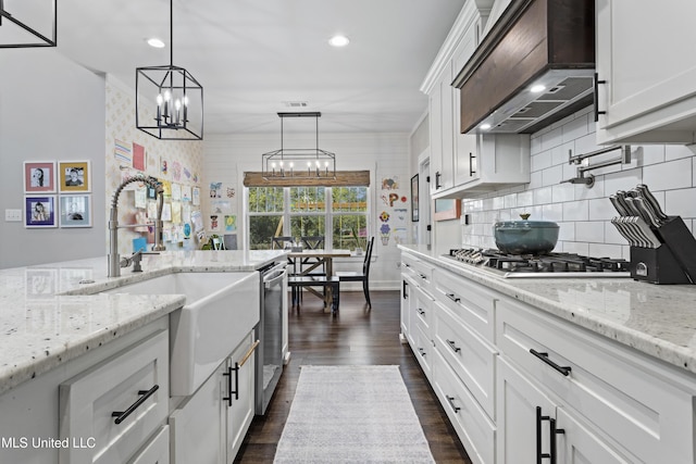 kitchen with custom exhaust hood, tasteful backsplash, appliances with stainless steel finishes, a sink, and an inviting chandelier