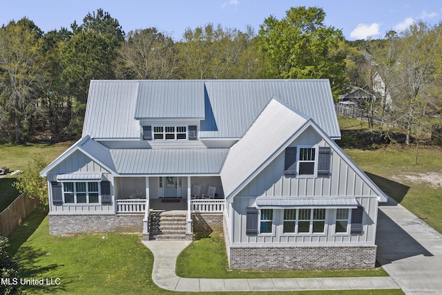 rear view of house with covered porch, board and batten siding, and a lawn