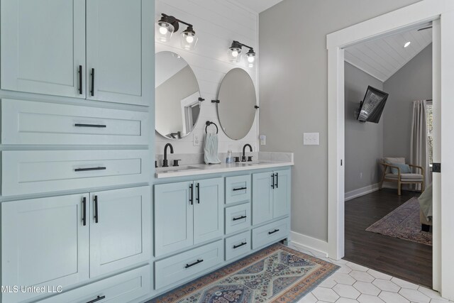 bathroom featuring double vanity, lofted ceiling, a sink, and tile patterned floors