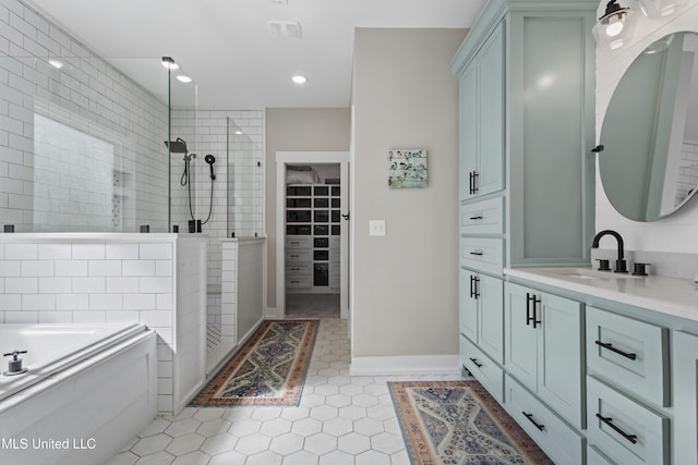 bathroom featuring a bath, tile patterned flooring, vanity, tiled shower, and a spacious closet