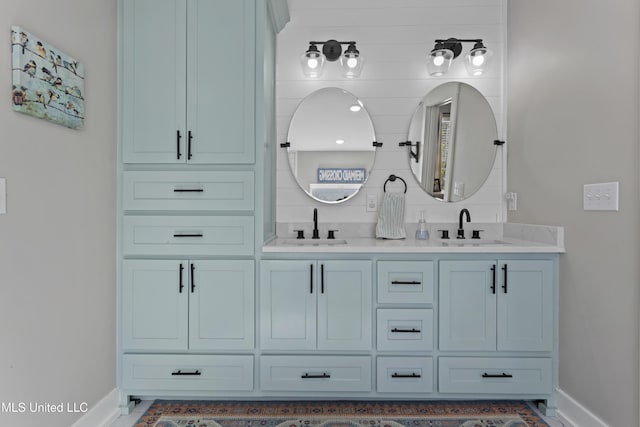 bathroom with double vanity, baseboards, and a sink