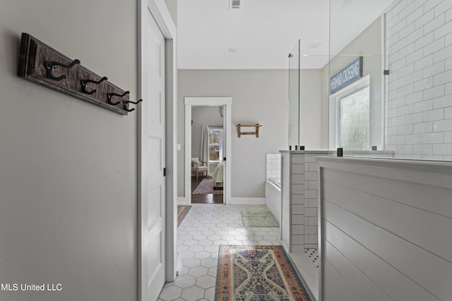 ensuite bathroom featuring connected bathroom, a walk in shower, tile patterned flooring, a bath, and baseboards