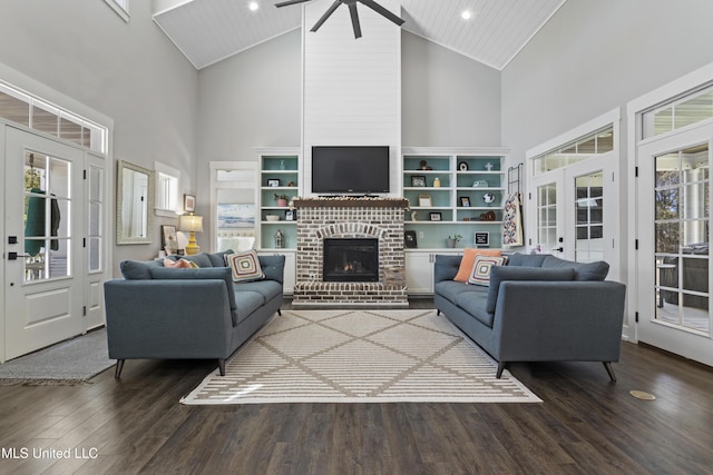 living area featuring a fireplace, wood finished floors, a healthy amount of sunlight, and a ceiling fan