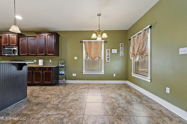 18225 Tulip Cv, Gulfport, MS 39503 - kitchen with stainless steel microwave, dark brown cabinets, a chandelier, decorative light fixtures, and light stone counters