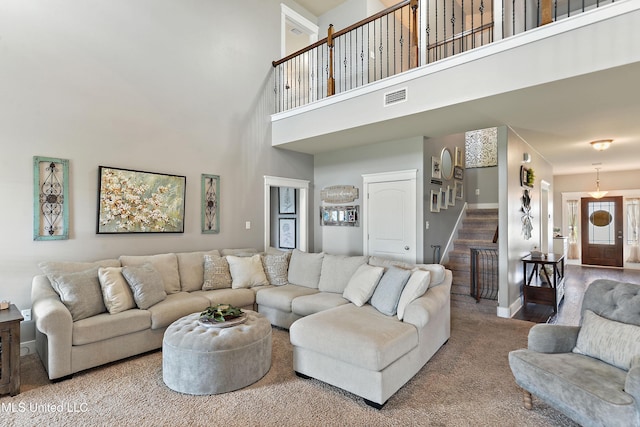 18225 Tulip Cv, Gulfport, MS 39503 - carpeted living room featuring stairway, baseboards, and a towering ceiling