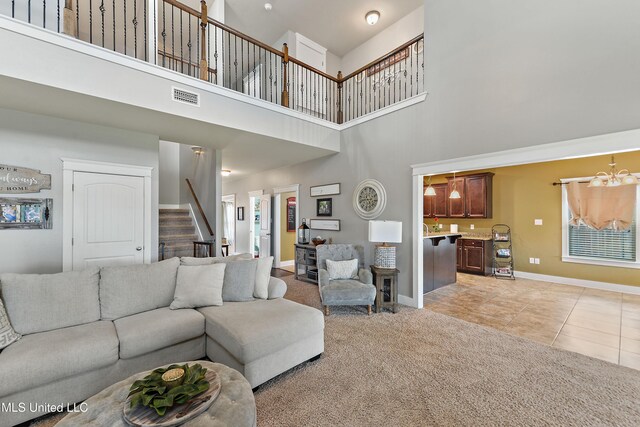 18225 Tulip Cv, Gulfport, MS 39503 - living room featuring a towering ceiling, stairs, light carpet, baseboards, and light tile patterned floors