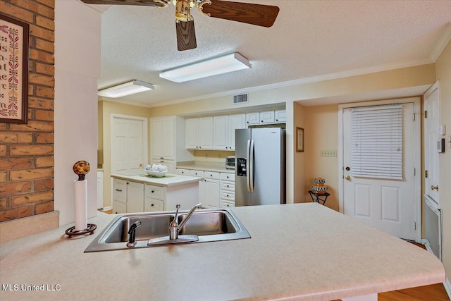 kitchen featuring stainless steel fridge, kitchen peninsula, sink, and a textured ceiling