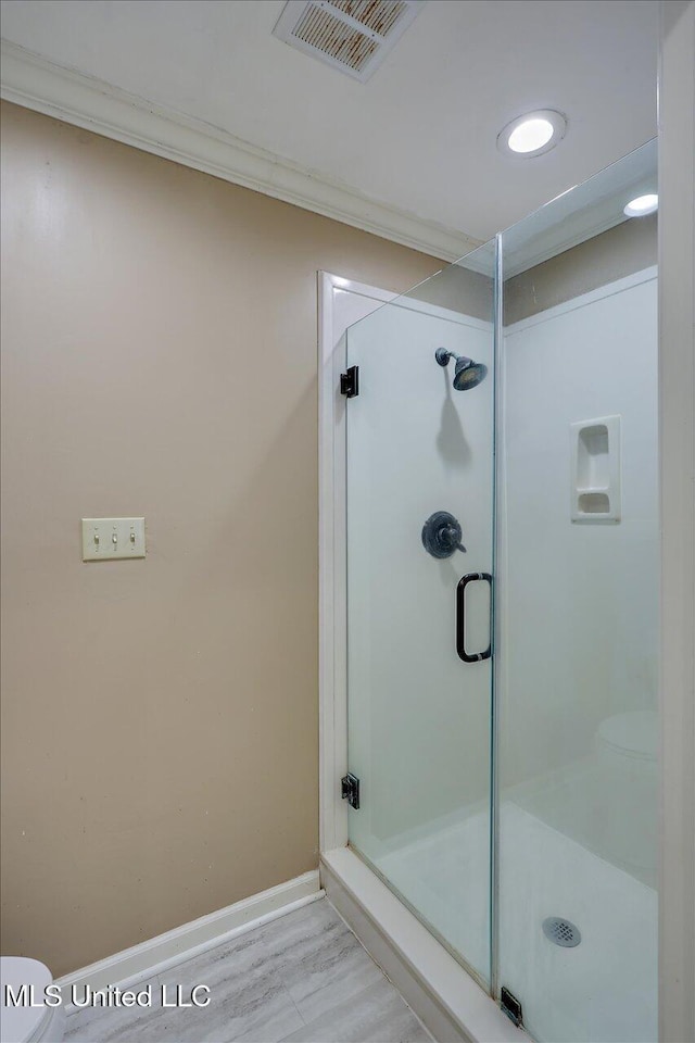 bathroom with ornamental molding, a shower with door, and toilet