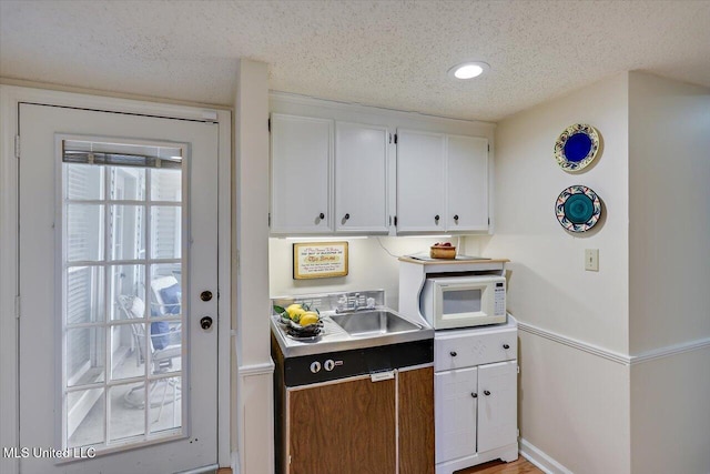 kitchen featuring sink, white cabinets, and a textured ceiling