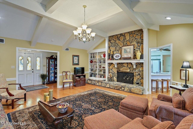 living room featuring a stone fireplace, vaulted ceiling with beams, an inviting chandelier, wood-type flooring, and built in features