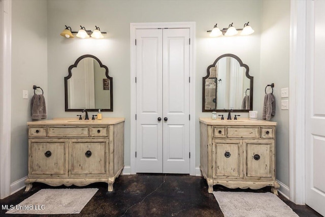 bathroom with baseboards, a sink, and two vanities