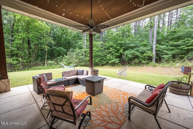 view of patio featuring a ceiling fan, outdoor lounge area, and a forest view