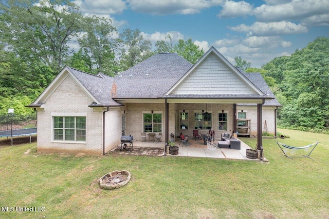 rear view of property featuring brick siding, a patio, a yard, and a trampoline