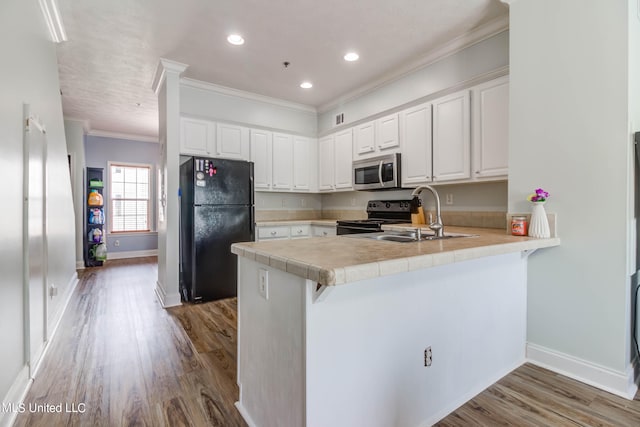 kitchen with black appliances, wood-type flooring, sink, kitchen peninsula, and white cabinetry