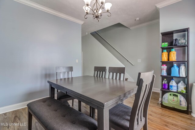 dining room with an inviting chandelier, crown molding, and light wood-type flooring