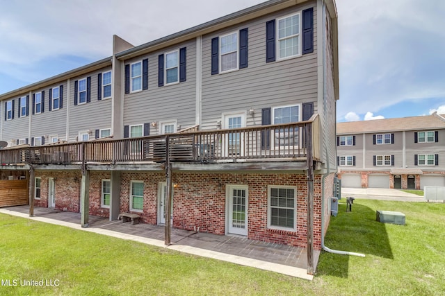 rear view of property with a garage, a lawn, and a balcony