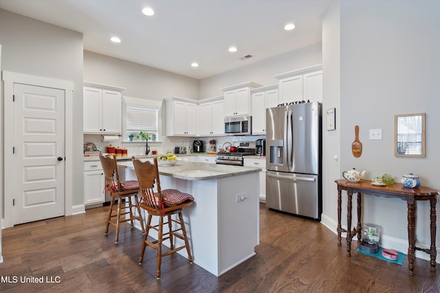 kitchen featuring a center island, appliances with stainless steel finishes, dark hardwood / wood-style floors, and white cabinets