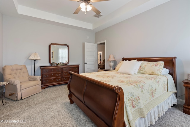 bedroom featuring a tray ceiling, carpet, and ceiling fan