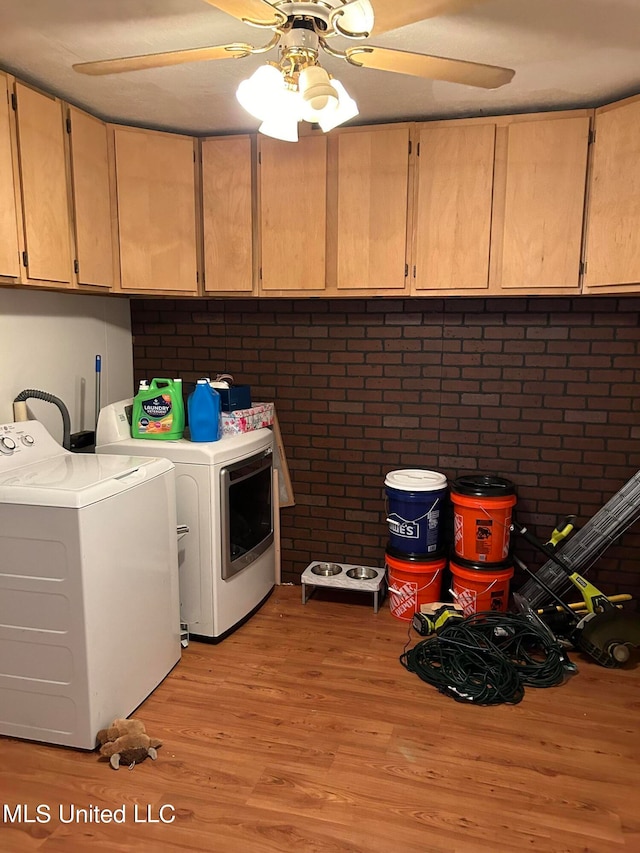 laundry room featuring cabinets, ceiling fan, light hardwood / wood-style flooring, independent washer and dryer, and brick wall