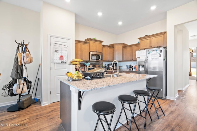 7785 Parkridge Dr, Southaven, MS 38671 - kitchen with appliances with stainless steel finishes, brown cabinets, light wood-style floors, a center island with sink, and recessed lighting