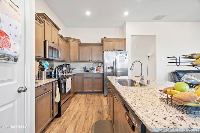 7785 Parkridge Dr, Southaven, MS 38671 - kitchen with appliances with stainless steel finishes, a sink, an island with sink, light wood-type flooring, and light stone countertops