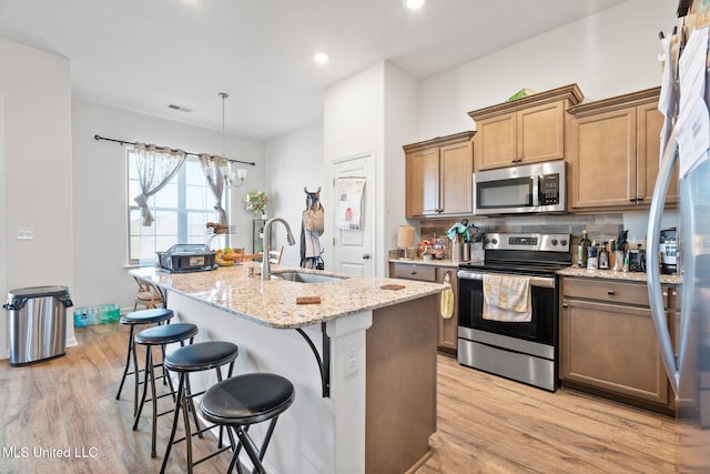 7785 Parkridge Dr, Southaven, MS 38671 - kitchen with appliances with stainless steel finishes, a sink, light wood-style flooring, a chandelier, and a kitchen bar