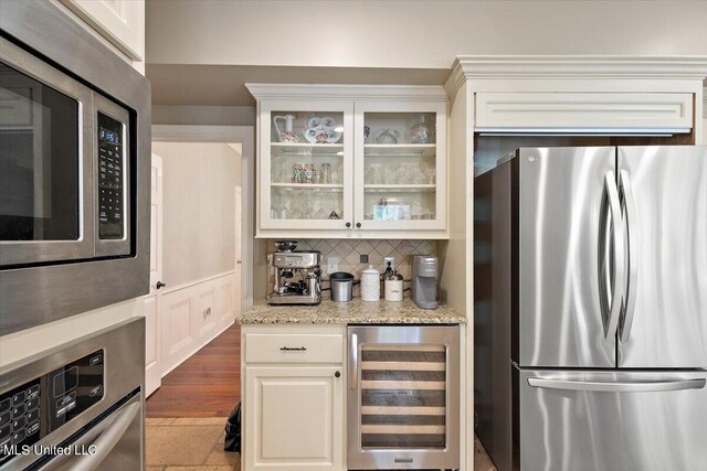 kitchen with tasteful backsplash, light stone counters, white cabinetry, stainless steel appliances, and wine cooler