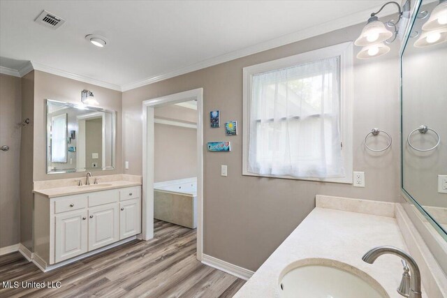 bathroom featuring vanity, crown molding, hardwood / wood-style floors, and a washtub