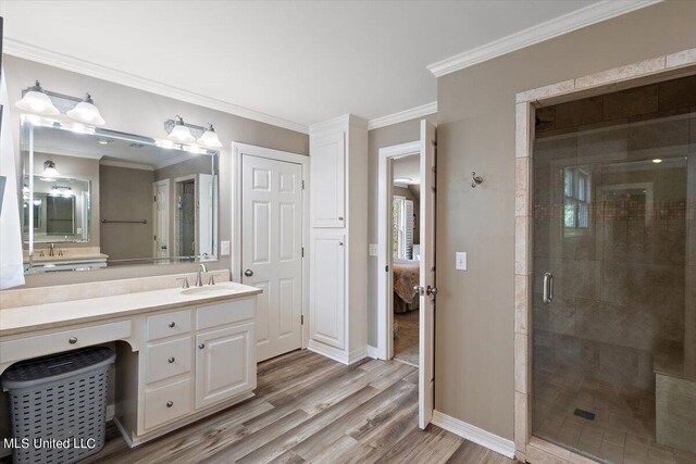 bathroom with vanity, ornamental molding, hardwood / wood-style flooring, and an enclosed shower