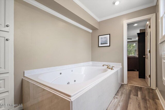 bathroom with crown molding, hardwood / wood-style floors, and a washtub