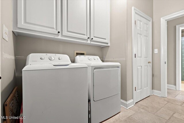 clothes washing area featuring separate washer and dryer and cabinets