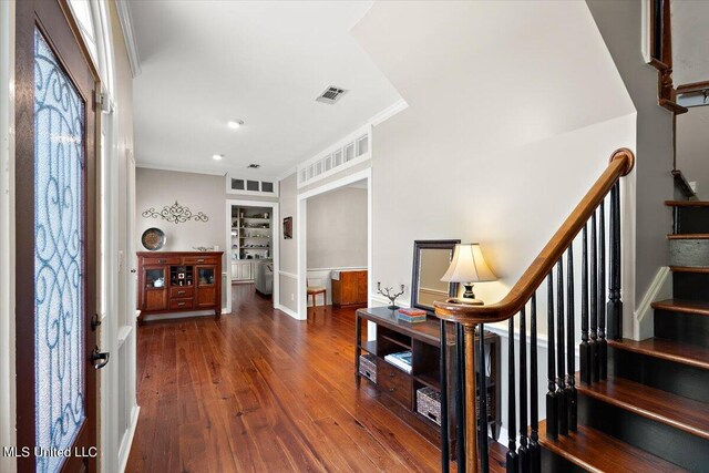 foyer with ornamental molding and dark wood-type flooring