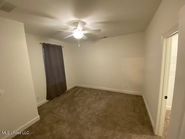 spare room with ceiling fan and dark carpet