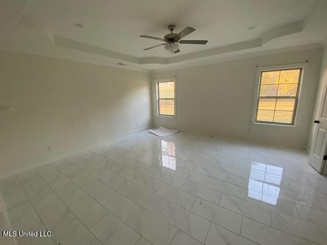 tiled spare room featuring a tray ceiling, ceiling fan, and plenty of natural light