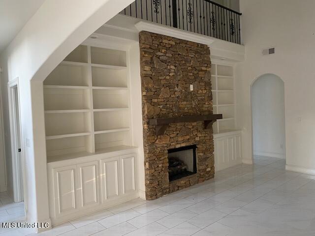 unfurnished living room featuring built in shelves and a towering ceiling