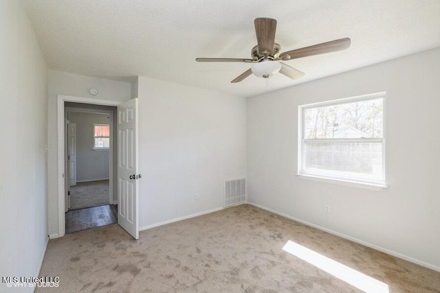 unfurnished bedroom featuring visible vents, multiple windows, carpet, and baseboards