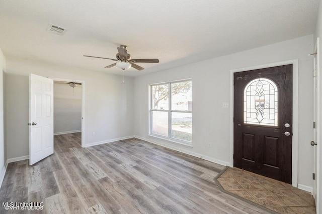 foyer entrance featuring baseboards, wood finished floors, visible vents, and ceiling fan