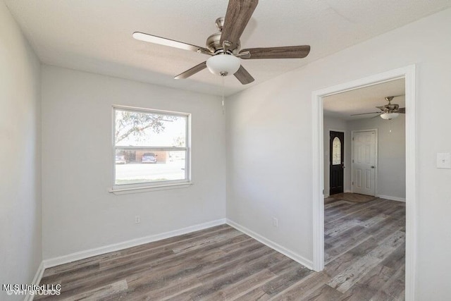 unfurnished room featuring baseboards, a ceiling fan, and wood finished floors