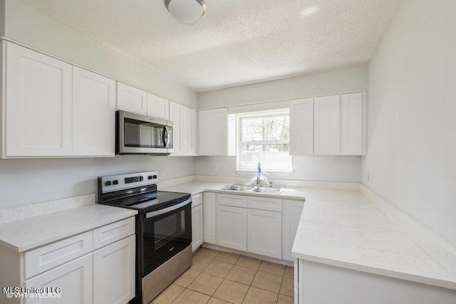 kitchen featuring a sink, a textured ceiling, appliances with stainless steel finishes, and white cabinetry