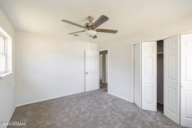 unfurnished bedroom featuring visible vents, a textured ceiling, a closet, carpet, and baseboards