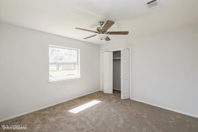 unfurnished bedroom featuring carpet, visible vents, baseboards, ceiling fan, and a closet