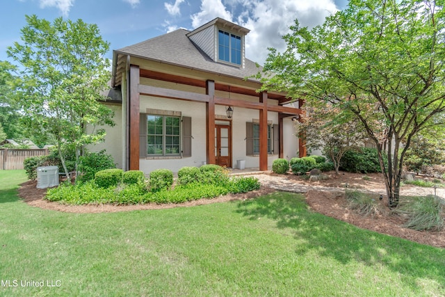 view of front of house featuring roof with shingles, a front lawn, and fence