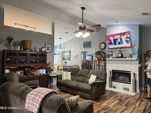 9958 Kahana St, Diamondhead, MS 39525 - living room featuring a tiled fireplace, ceiling fan, wood finished floors, a chandelier, and high vaulted ceiling