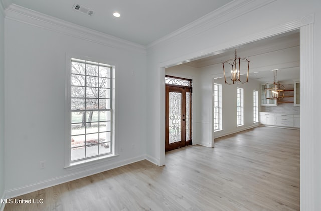 entryway with light hardwood / wood-style floors, a chandelier, a healthy amount of sunlight, and crown molding