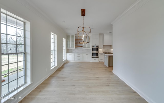 kitchen with ornamental molding, white cabinetry, tasteful backsplash, and hanging light fixtures