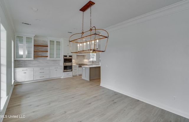 kitchen with stainless steel appliances, a center island, white cabinetry, decorative light fixtures, and backsplash